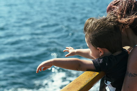 woman hugging a boy near clam body of water on daytime thumbnail