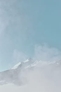 hill covered by snow under white clouds and blue sky thumbnail