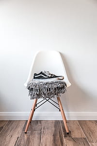 pair of black-and-white Vans Old Skool skate shoes on bar stool beside wall thumbnail