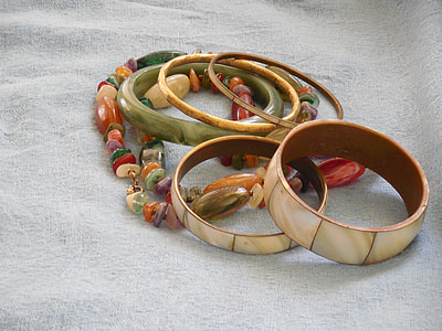 five ceramic bangles above multi-colored beaded necklace in gray textile thumbnail
