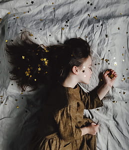 girl lying on gray textile with gold star glitters thumbnail