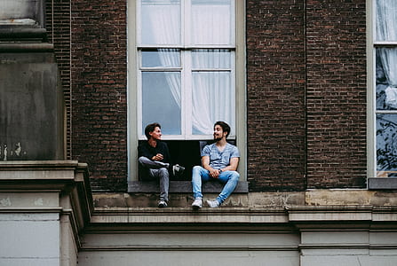 two man sitting on building window thumbnail