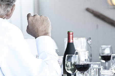 man leaning on table near wine bottle and wine glass thumbnail