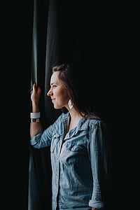 selective focus photo of woman standing and looking outside thumbnail