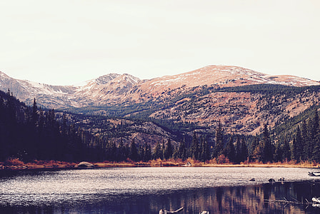 trees and mountains reflection on calm body of water at daytime thumbnail