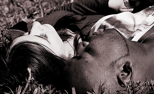 black and white photo of man and woman laying on graa thumbnail