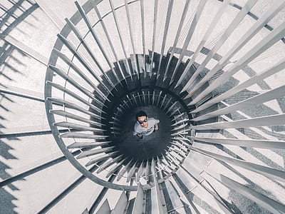 man standing below gray spiral staircases thumbnail