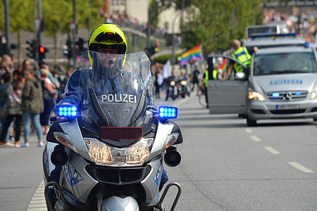 male police officer riding gray touring motorcycle with blue blinkers turned on at daytime thumbnail