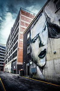 painting of woman on concrete wall under cloudy sky thumbnail