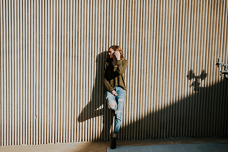 woman leaning with one foot on wall during daytime thumbnail