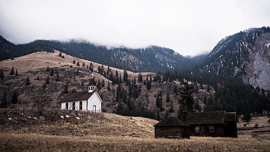 two black and white painted sheds on mountain taken under white clouds during daytime thumbnail