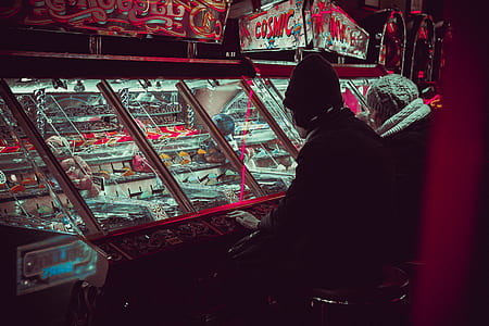 person in black jacket beside arcade game thumbnail
