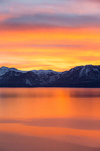 panoramic photo of snow-capped mountains beside body of water during golden hour thumbnail