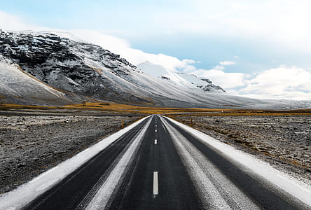 concrete road near slow-covered mountain under cloudy sky thumbnail