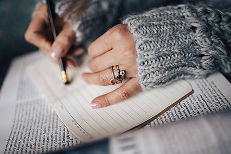 Woman in a grey sweater taking notes in an organizer thumbnail