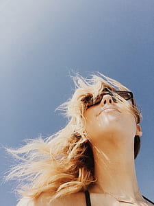 low angle photo of smiling woman under blue and white sky thumbnail
