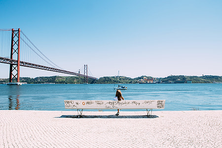 person sitting on bench near body of water photo thumbnail