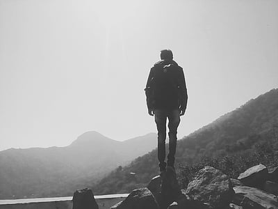 man standing on cliff grayscale photography thumbnail
