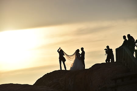 silhouette of bride and groom on hill at golden hour thumbnail
