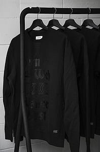 black crew-neck sweaters hanging on black steel clothes rack thumbnail