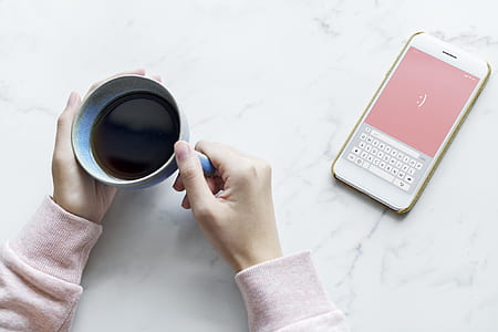 person holding cup of coffee leaning on marble tile thumbnail
