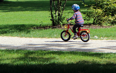 boy wearing helmet riding red bicycle on road during daytime thumbnail