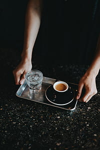filled clear drinking glass and black cup on top of gray tray thumbnail