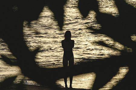 silhouette photo of woman standing near body of water thumbnail