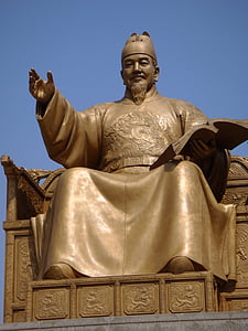 monk statue raising hand while holding book thumbnail