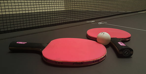 two red ping pong paddles beside of white ball thumbnail