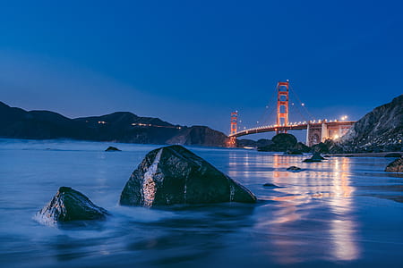 body of water under bridge at night time thumbnail
