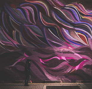 minimalist photography of person walking along graffiti wall thumbnail