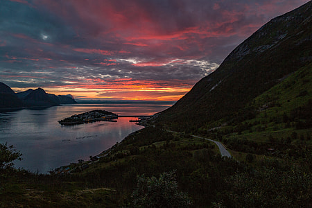 view of body of water beside mountain during dawn thumbnail