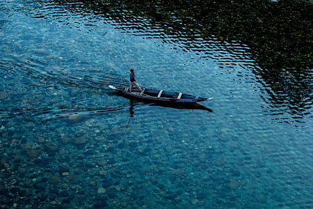 bird's eye view of man on black boat thumbnail