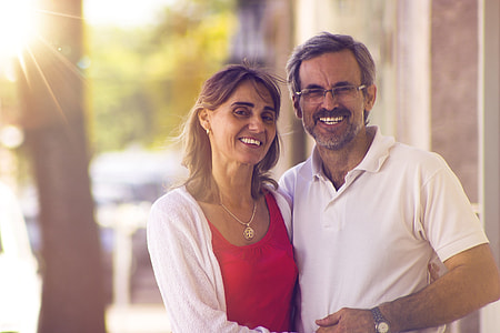 man wearing white polo shirt hugging with woman wearing white cardigan and red top thumbnail