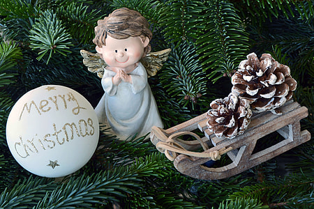 white Merry Christmas bauble beside angel figurine and brown sled thumbnail
