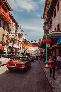 vehicles traveling on road between buildings during daytime thumbnail
