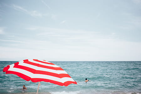 A beach umbrella with people swimming in the background thumbnail