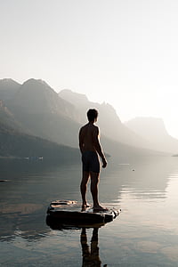 man standing on rock surrounded by body of water thumbnail
