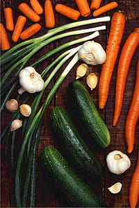 cucumber; garlic; carrots; and spring onions on brown wooden surface thumbnail