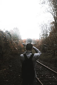 man beside train railway between bush thumbnail