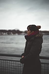 person standing near fence facing the sea thumbnail