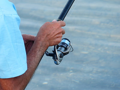 person holding black fishing reel thumbnail