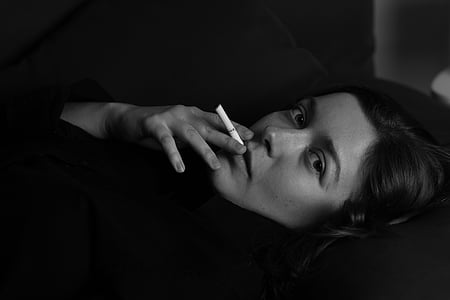 grayscale photo of lying woman while smoking thumbnail