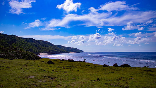 body of water beside mountain with cloudy sky thumbnail