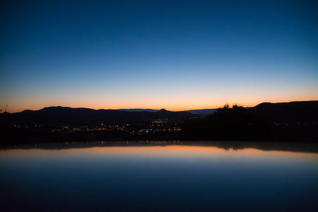 silhouette of buildings with lights view from body of water thumbnail