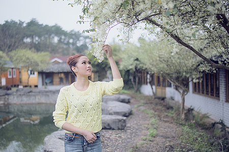 woman wearing green knitted sweater holds white flower at daytime thumbnail
