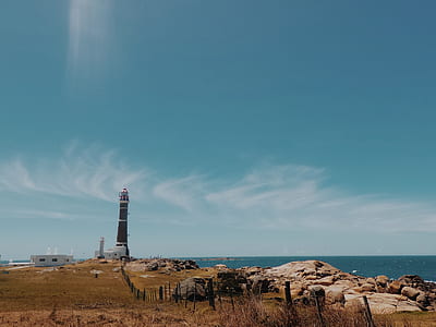 view of brown light house near on body of water thumbnail
