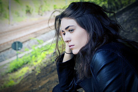 woman sitting on hill near road thumbnail