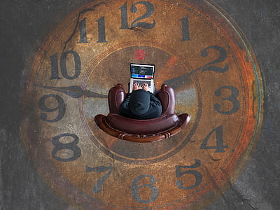 top view photography of man sitting on brown leather sofa chair while using gray and black laptop computer thumbnail